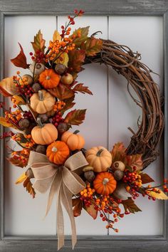 a wreath with pumpkins and leaves on it