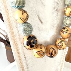 a necklace made out of wooden beads with black and white designs on them sitting on a table