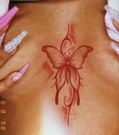 a woman's back with a butterfly tattoo on her left side and pink nail polish