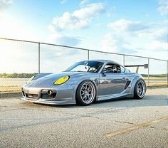 a silver sports car parked in front of a fence