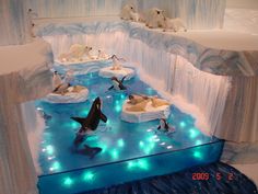 an ice sculpture with penguins and polar bears in the water, surrounded by blue lights