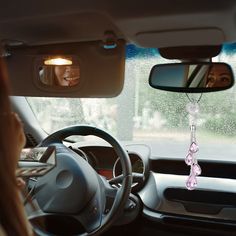 a woman is sitting in the driver's seat of a car and looking at her reflection