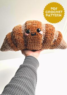 a person holding up a stuffed animal made out of crocheted material with googly eyes