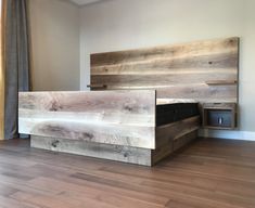 a bed made out of wood sitting on top of a hard wood floor next to a window