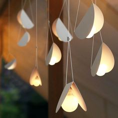 a group of lights hanging from a wooden beam in the air with paper boats on them