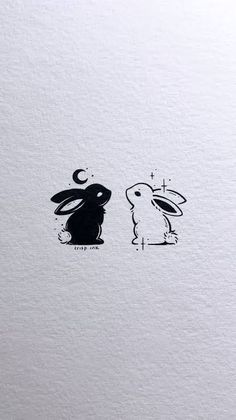 two rabbits sitting next to each other on top of a white paper with black ink