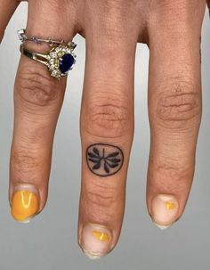 a woman's hand with two rings on it and a dragon tattoo on the middle finger