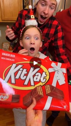 two people holding up a box of kitkats in front of their faces and making silly faces