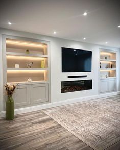 an empty living room with built in shelves and a flat screen tv on the wall