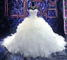 a white wedding dress on display in front of a blue wall