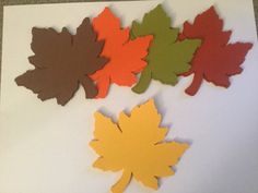 four pieces of cut out paper with different colored leaves on top of each other, sitting on a table