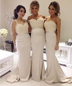 three beautiful women standing next to each other in front of a white table with flowers on it