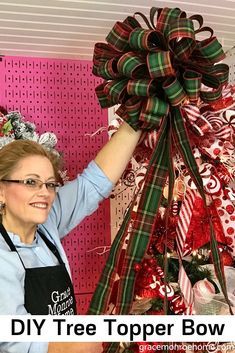 a woman holding up a large bow in front of a christmas tree with candy canes on it