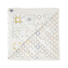 a quilted blanket with geometric designs on the front and back, folded in white