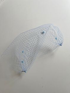 a white object with blue dots on it's head and net covering the top