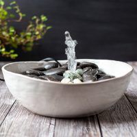 a bowl filled with rocks and water spouting out of it's side