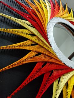 a close up of a circular object made out of colored paper and wire with a mirror in the middle