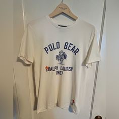 Polo Bear Graphic Tee. Super Soft Cotton, Ivory Body With “Ranch Bear” Graphic On Front, “Hand Written” Script And Embroidered Embellishments On Front And Back. Custom-Fit Medium. Nwot. Never Been Worn. Cream Casual Tops With Embroidered Logo, Casual Cream Tops With Embroidered Logo, White Embroidered Graphic Tee, Classic Embroidered Cream Top, Classic Cream Embroidered Top, White Casual Shirt With Embroidered Graphics, Casual White Shirt With Embroidered Graphics, White Cotton Shirt With Embroidered Graphics, Classic Cotton Top With Embroidered Graphics