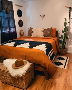 a bed with an orange blanket and black and white bedspread in a bedroom