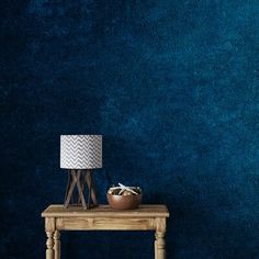 a wooden table with a lamp on it in front of a blue wall and floor