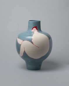 a blue and white vase with a woman's body painted on the side, sitting in front of a gray background