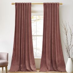 a living room with a large window covered in pink curtains and a chair next to it