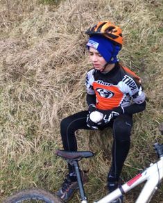 a young boy sitting on top of a bike next to a pile of dirt and grass