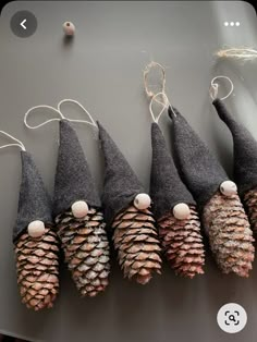 several cones are lined up on a table with string and pinecones hanging from them