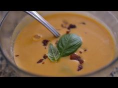 a glass bowl filled with soup and topped with a leaf