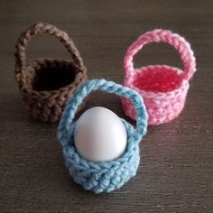 three crocheted baskets with an egg in one and a plastic ball in the other