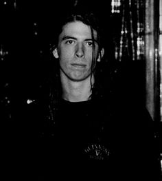 a black and white photo of a man with long hair in front of a window