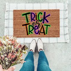 a person standing in front of a door mat with the words trick or treat written on it