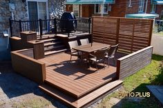 a wooden deck with chairs and table next to a house