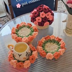 three crocheted coasters sitting on top of a table next to a coffee cup