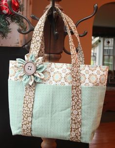 a handbag with a flower on it sitting on top of a wooden stand next to a christmas tree