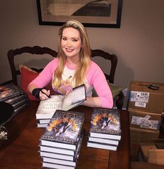 a woman sitting at a table with many books