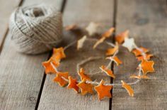 an orange and white star garland next to a ball of yarn on a wooden table