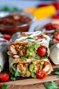 two burritos stacked on top of each other with tomatoes and guacamole