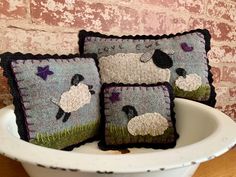 three sheep pillows sitting on top of a white bowl