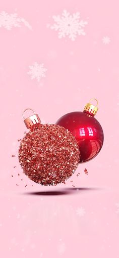 a red ornament with glitter on it in front of a pink background and snowflakes