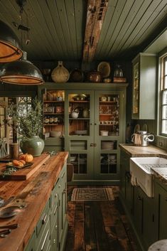 an old fashioned kitchen with green cabinets and wood flooring on the walls, along with wooden counter tops