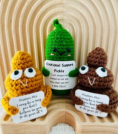 three crocheted stuffed animals holding signs in front of a wooden stand with text on it