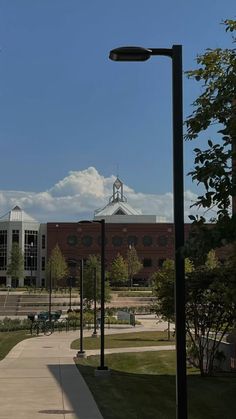 a street light sitting on the side of a road next to a building with a clock tower in the background