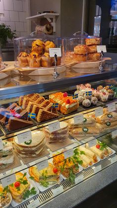 a display case filled with lots of different types of sandwiches and pastries on trays