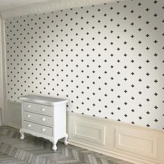 a white dresser sitting next to a wall with black crosses on it's side