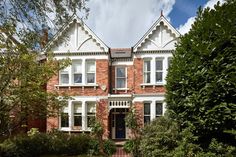 a large brick house with white trim on the front and side windows, surrounded by greenery