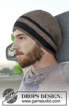 a man with a beard wearing a beanie and holding a skateboard in his hand