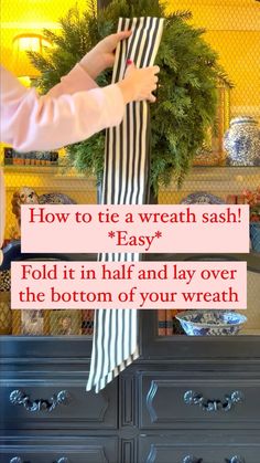 someone is placing a wreath on top of a dresser with the words, how to tie a wreath sash? easy fold it in half and lay over the bottom of your