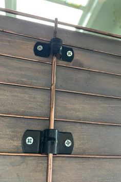 two black latches are attached to the side of a wooden structure with wood slats