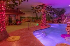 an indoor swimming pool is lit up with christmas lights and palm trees in the background